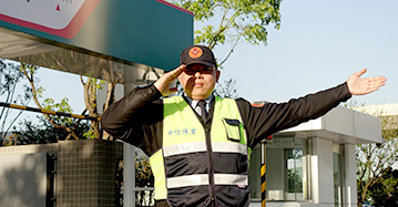 優質服務介紹一,駐衛保全服務,一名穿反光背心的保全人員站在停車場前指揮車輛